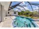 Private screened-in pool with patio, lush landscaping, and blue accents at 1304 Alton Rd, Port Charlotte, FL 33952