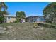 Rear exterior of home featuring a spacious yard and screened-in lanai with mature trees at 149 Small Se St, Port Charlotte, FL 33952