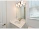Well-lit bathroom featuring a white single sink vanity and a window with blinds at 15033 Shady Palms Ln, Nokomis, FL 34275
