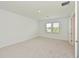 A bright bedroom featuring neutral carpet, white walls, two sunny windows, and a closet at 15033 Shady Palms Ln, Nokomis, FL 34275