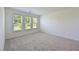 Bright, carpeted bedroom with three windows offering natural light and backyard views at 15033 Shady Palms Ln, Nokomis, FL 34275