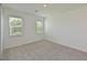 Bright bedroom featuring neutral carpet, white walls, and two sunny windows overlooking the lawn at 15033 Shady Palms Ln, Nokomis, FL 34275