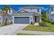 Charming two-story home featuring a gray garage door, a red front door, and manicured lawn at 15033 Shady Palms Ln, Nokomis, FL 34275