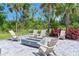 Outdoor fire pit area with modern concrete fire pit, surrounded by chairs and lush landscaping at 15033 Shady Palms Ln, Nokomis, FL 34275