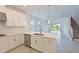 Beautiful white kitchen with modern appliances, island, and view into adjacent sunroom at 15033 Shady Palms Ln, Nokomis, FL 34275