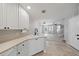 Kitchen with white cabinets and stone tile floors opens up into a living room area at 1519 Napoli E Dr, Sarasota, FL 34232