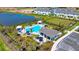 Aerial view of a community pool with cabanas, lounge chairs, lush landscaping, clubhouse, lake and ample parking at 16646 San Nicola Pl, Bradenton, FL 34211