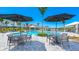 Community pool with lounge chairs, umbrellas, tables, and lush landscaping, creating a resort-style atmosphere at 16646 San Nicola Pl, Bradenton, FL 34211