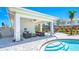 Outdoor pool house area featuring comfortable lounge chairs, lush landscaping, and a covered seating area with a grill at 16646 San Nicola Pl, Bradenton, FL 34211