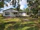A sprawling backyard featuring lush greenery and mature trees surrounding a charming home with a covered patio at 1802 19Th W Ave, Bradenton, FL 34205
