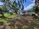 A charming backyard features mature trees and ample green space surrounding a quaint white home with a covered patio at 1802 19Th W Ave, Bradenton, FL 34205