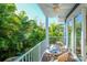 Balcony with wooden table and chairs surrounded by lush landscaping and views of nearby buildings at 211 65Th St, Holmes Beach, FL 34217