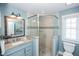 Stylish bathroom with a glass-enclosed shower, granite countertop, and coastal-themed mirror at 211 65Th St, Holmes Beach, FL 34217