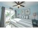 Comfortable bedroom with gray and white bedding, ceiling fan, and balcony entrance for natural light at 211 65Th St, Holmes Beach, FL 34217