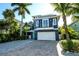 Charming coastal-style home featuring a two-car garage, a quaint balcony, and lush tropical landscaping at 211 65Th St, Holmes Beach, FL 34217