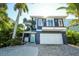 Two-story home with a blue facade, balcony, two car garage and lush, tropical landscaping at 211 65Th St, Holmes Beach, FL 34217