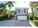 Charming coastal-style home featuring a two-car garage, a quaint balcony, and lush tropical landscaping at 211 65Th St, Holmes Beach, FL 34217