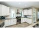 Well-lit kitchen showcasing white cabinets, stainless steel appliances, and durable granite countertops for cooking at 211 65Th St, Holmes Beach, FL 34217
