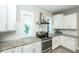 Kitchen with white cabinets and stainless steel appliances, illuminated by natural light from the windows at 211 65Th St, Holmes Beach, FL 34217
