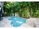 Backyard pool surrounded by lush greenery, with a stone feature and spa at 211 65Th St, Holmes Beach, FL 34217