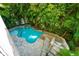Aerial view of a backyard oasis featuring a pool with slide and spa surrounded by lush landscaping at 211 65Th St, Holmes Beach, FL 34217