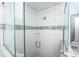 Close up of a glass door shower with white tile featuring decorative gray tile stripe at 211 65Th St, Holmes Beach, FL 34217