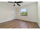 This bedroom features a ceiling fan and a window overlooking green trees and landscaping at 2477 Wood Oak Dr, Sarasota, FL 34232
