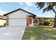 Charming single-story home featuring a red door, stone accents, and well-maintained landscaping at 2477 Wood Oak Dr, Sarasota, FL 34232