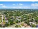Expansive aerial view of a charming home nestled among lush greenery and mature trees, with a clear blue sky above at 3988 Berlin Dr, Sarasota, FL 34233