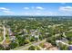 Expansive aerial view of a charming home nestled among lush greenery and mature trees, with a clear blue sky above at 3988 Berlin Dr, Sarasota, FL 34233