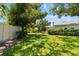Expansive backyard with lush green grass and mature trees, with glimpses of the house beyond the manicured hedges at 3988 Berlin Dr, Sarasota, FL 34233
