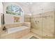 Bathroom featuring a tub, glass shower, arched window, and tile flooring at 3988 Berlin Dr, Sarasota, FL 34233