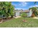 Landscaped backyard featuring a lush lawn and tropical foliage, with a peek at the screened-in pool at 4322 Concert St, Port Charlotte, FL 33948