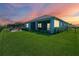 A manicured lawn leads to a screened porch and cozy patio area with outdoor seating and beautiful sunset views at 4407 Big Woods Way, Parrish, FL 34219