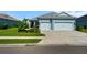 Charming blue home featuring a well-maintained lawn and a two-car garage with a concrete driveway at 4407 Big Woods Way, Parrish, FL 34219