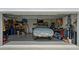 View of the open garage showcasing storage, tools, and a car covered with a tarp at 4407 Big Woods Way, Parrish, FL 34219