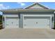 Close-up of a two-car garage with carriage doors, enhanced by stylish exterior lighting and a concrete driveway at 4407 Big Woods Way, Parrish, FL 34219
