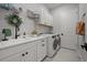 Modern laundry room featuring a sink, white cabinets, a wreath and a new washer and dryer at 4407 Big Woods Way, Parrish, FL 34219