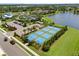 Aerial view of blue and green pickleball courts beside parking and a lake in a community with many trees at 4407 Big Woods Way, Parrish, FL 34219
