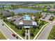Aerial view of a community clubhouse and resort style pool, surrounded by palm trees and manicured landscaping at 4407 Big Woods Way, Parrish, FL 34219