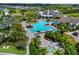 Aerial view of a resort-style pool and hot tub, surrounded by lush palm trees and a beautiful community landscape at 4407 Big Woods Way, Parrish, FL 34219