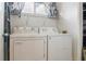 Well-lit laundry room with a white washer and dryer, shelf, and curtained window at 4475 Sandner Dr, Sarasota, FL 34243