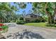 Two-story home with a long driveway, lush greenery, and mature trees on a large lot at 4917 Leatha Ln, Sarasota, FL 34232