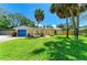 Charming yellow single-story home featuring a blue garage door and well-manicured lawn and arched entry at 5223 Shadow Lawn Dr, Sarasota, FL 34242
