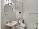 Half bathroom with a round mirror, commode, and unique pink wash basin at 5224 58Th E Ter, Bradenton, FL 34203