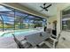 Screened-in pool area with dining table, ceiling fan, and scenic lake view with palm trees at 5319 120Th E Ave, Parrish, FL 34219