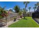 Landscaped backyard featuring lush green lawn, palm trees, and a wooden fence with flowering shrubs at 5581 Shadow Lawn Dr, Sarasota, FL 34242