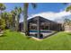 Lush backyard featuring a pool with a screened enclosure, grassy area, and palm trees at 5581 Shadow Lawn Dr, Sarasota, FL 34242