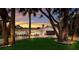 Charming one-story home with a well-manicured lawn, mature trees, and a brick driveway with a warm sunset glow at 5581 Shadow Lawn Dr, Sarasota, FL 34242