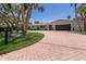 Beautiful single-story home with a circular brick paver driveway and a lush green lawn with palm trees at 5581 Shadow Lawn Dr, Sarasota, FL 34242